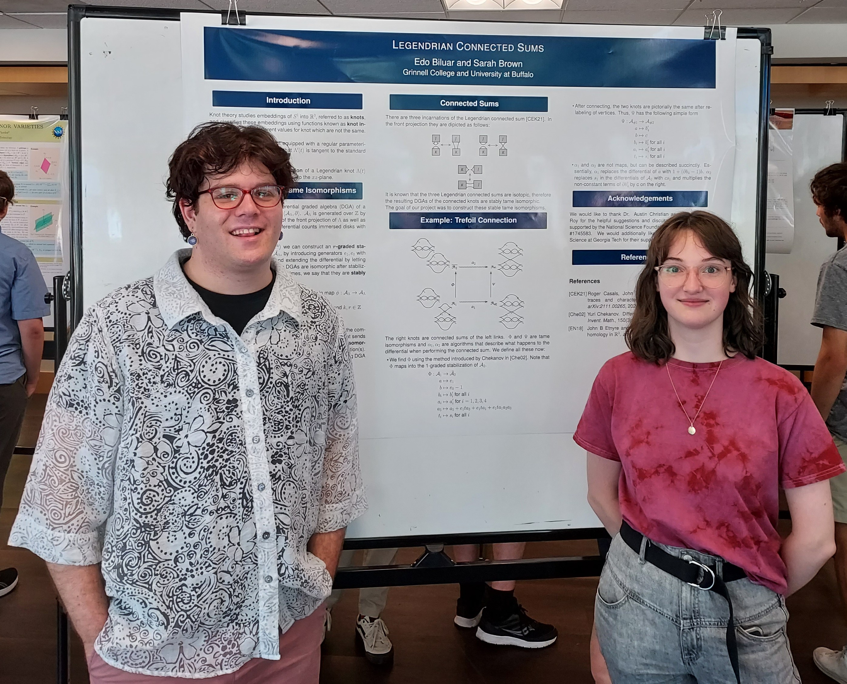 Mathematicians Edo Biluar and Sarah Brown standing in front of their poster 'Legendrian connected sum'